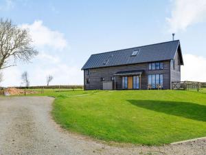 a house on a grassy field next to a gravel road at 3 Bed in Ashreigney 65743 in Ashreigney