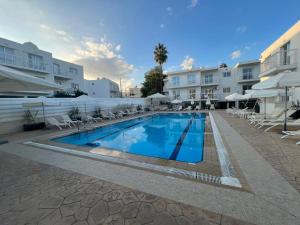 una piscina con sillas y sombrillas en un hotel en Tangerine Studio with Pool in Ayia Napa en Ayia Napa
