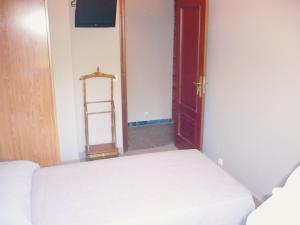 Habitación pequeña con cama y puerta en Pensión Bos, en Bergondo