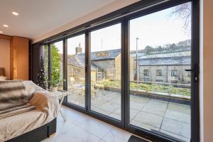 a room with large windows and a chair and a balcony at Host & Stay - Pâl Lodge in Holmfirth