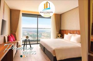 um quarto de hotel com uma cama e uma grande janela em Beach Condotel - Apec Phú Yên em Tuy Hoa