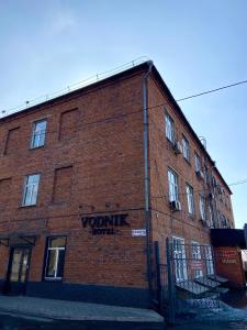 a brick building with a sign on the side of it at Vodnik Hotel in Semey