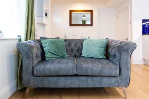 a blue couch with two green pillows on it at Westminster Suites by Sorted Stay in Southend-on-Sea