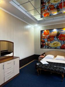 een slaapkamer met een bed en een schilderij aan de muur bij Vodnik Hotel in Semey