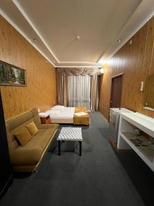 een hotelkamer met een bed en een bank bij Vodnik Hotel in Semey