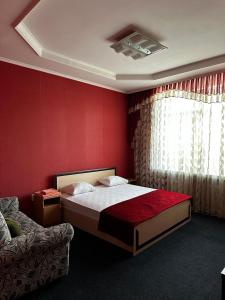 a bedroom with a bed and a red wall at Vodnik Hotel in Semey