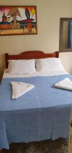 un letto con coperta blu e cuscini bianchi di Hotel Veleiro de Porto a Porto De Galinhas