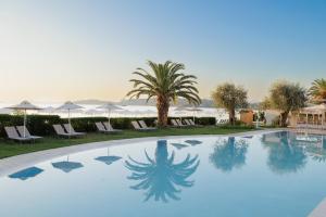 a swimming pool with palm trees and umbrellas at Elea Beach Hotel in Dassia +170 photos