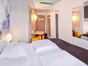 una camera d'albergo con due letti e uno specchio di B&B Hotel Mainz-Hbf a Magonza