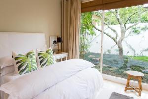 1 dormitorio con cama blanca y ventana grande en Lexden Guesthouse, en Pietermaritzburg