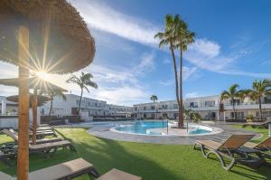 un complexe avec une piscine et des palmiers dans l'établissement Hotel Siroco - Adults Only, à Costa Teguise