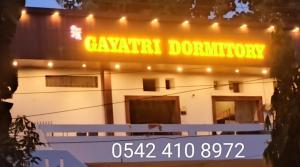 Maa Gayatri Dormitory في فاراناسي: مبنى أبيض عليه لافتة نيون