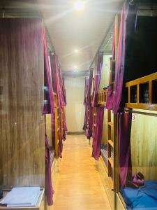 un couloir d'un train avec des rideaux violets dans l'établissement Maa Gayatri Dormitory, à Varanasi