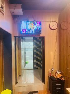 Maa Gayatri Dormitory في فاراناسي: حمام مع تلفزيون على الحائط وغرفة مع باب