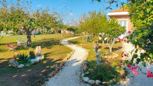 un giardino alberato e un sentiero di fronte a una casa di Villa Chimera a Pachino