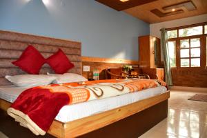 um quarto com uma cama grande e almofadas vermelhas em Guruchhaya hotel and cottages em Manali