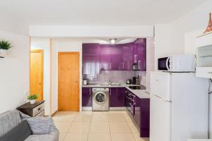 een keuken met paarse kasten en een wasmachine en droger bij Apartamento en el centro a un minuto de la playa in Benidorm