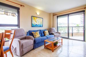 ein Wohnzimmer mit einem blauen Sofa und einem Tisch in der Unterkunft ESPACIO 3 - Primera Línea de Playa in Cullera