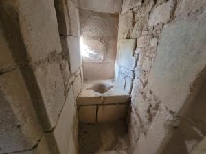 a stone room with a toilet in a stone wall at La Cour du Château in La Charité-sur-Loire