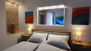 a bedroom with a bed with two lamps and a mirror at Studio EMA - Tartini Square in Piran