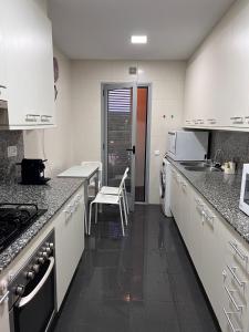 una cocina con armarios blancos y fregadero en FIRA Gran Vía 2 - Private Rooms in a Shared Apartment - Habitaciones Privadas en Apartamento Compartido, en Hospitalet de Llobregat