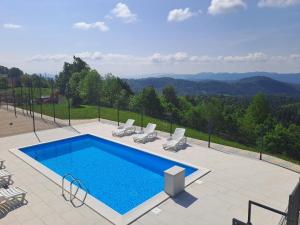 a swimming pool with chairs and a view of the mountains at Holiday Home with Hot tub and Sauna Sabina in Rovte