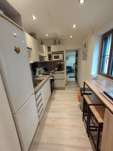 una cucina con elettrodomestici bianchi e pavimenti in legno di Petit gîte bleu 