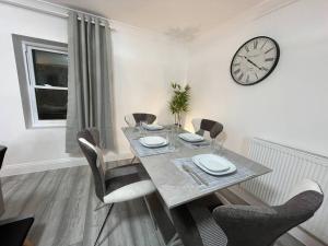 Modern & Stylish Haven In Heart of London في لندن: غرفة طعام مع طاولة وساعة على الحائط
