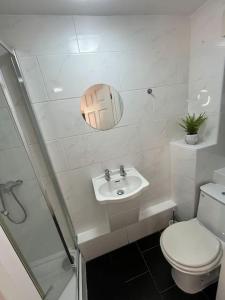 Baño blanco con aseo y lavamanos en Modern & Stylish Haven In Heart of London, en Londres
