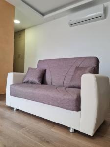 - un canapé blanc avec des coussins violets dans l'établissement Cocktail Apartment, à San Pawl il-Baħar