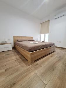 a bedroom with a large bed and a wooden floor at Cocktail Apartment in St. Paul's Bay