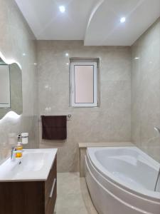 La salle de bains blanche est pourvue d'une baignoire et d'un lavabo. dans l'établissement Cocktail Apartment, à San Pawl il-Baħar