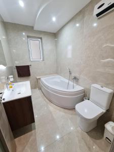 La salle de bains est pourvue d'une baignoire, de toilettes et d'un lavabo. dans l'établissement Cocktail Apartment, à San Pawl il-Baħar