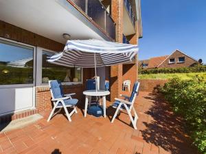 a patio with a table and two chairs and an umbrella at Düne 76 Moderne Ferienwohnung in Baltrum
