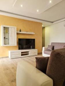 - un salon avec une télévision et un canapé dans l'établissement Cocktail Apartment, à San Pawl il-Baħar