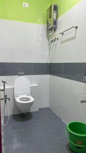 a bathroom with a toilet and a green and white wall at Supritha Homestay Hampi in Hampi