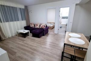 ein Wohnzimmer mit einem lila Sofa und einem Tisch in der Unterkunft Apartament CWA 3 Aeroport Otopeni in Otopeni
