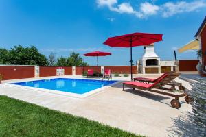 einen Pool mit zwei Stühlen und zwei roten Sonnenschirmen in der Unterkunft Activity villa Marula with outdoor pool in Buje in Gamboci