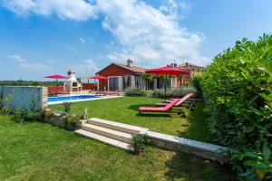 ein Haus mit einem Pool und roten Sonnenschirmen im Hof in der Unterkunft Activity villa Marula with outdoor pool in Buje in Gamboci
