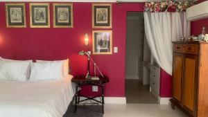 a bedroom with a bed and a red wall at Residence William French in Simonʼs Town