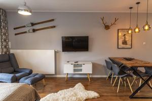 uma sala de estar com uma mesa e uma televisão na parede em VacationClub – Bukowa 17A Apartament E.1 em Wisla