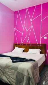 a bedroom with a pink wall with a bed at Supritha Homestay Hampi in Hampi