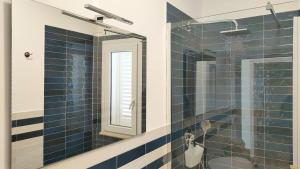 a blue tiled bathroom with a shower and a mirror at Villa Chimera in Pachino
