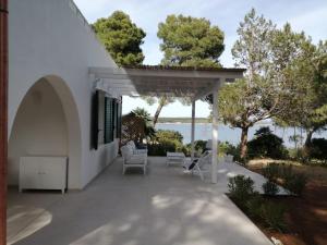 een witte patio met stoelen en een pergola bij Seaview Villa Lazzaretto in Fertilia