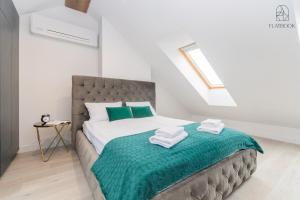 a bedroom with a bed with green and white towels at Flatbook Apartamenty - Jantar Park in Jantar