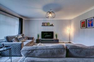 een woonkamer met een bank en een tv bij Ravenscroft - Coorie Doon in Irvine