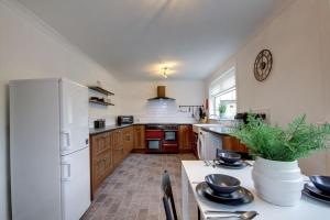 a kitchen with a white refrigerator and a table at Ravenscroft - Coorie Doon in Irvine