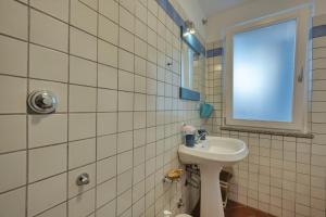 ein weiß gefliestes Bad mit einem Waschbecken und einem Fenster in der Unterkunft Casa Celeste - Goelba in Pomonte