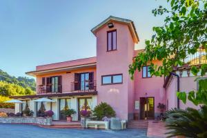 una casa rosa con un patio enfrente en La Casa delle Monache Country Resort, en Motta Camastra
