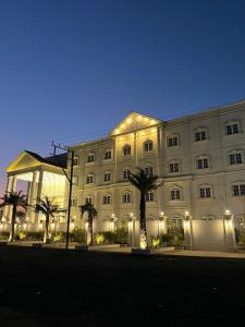 a large white building with palm trees in front of it at Pride Resort, Rajkot in Rajkot